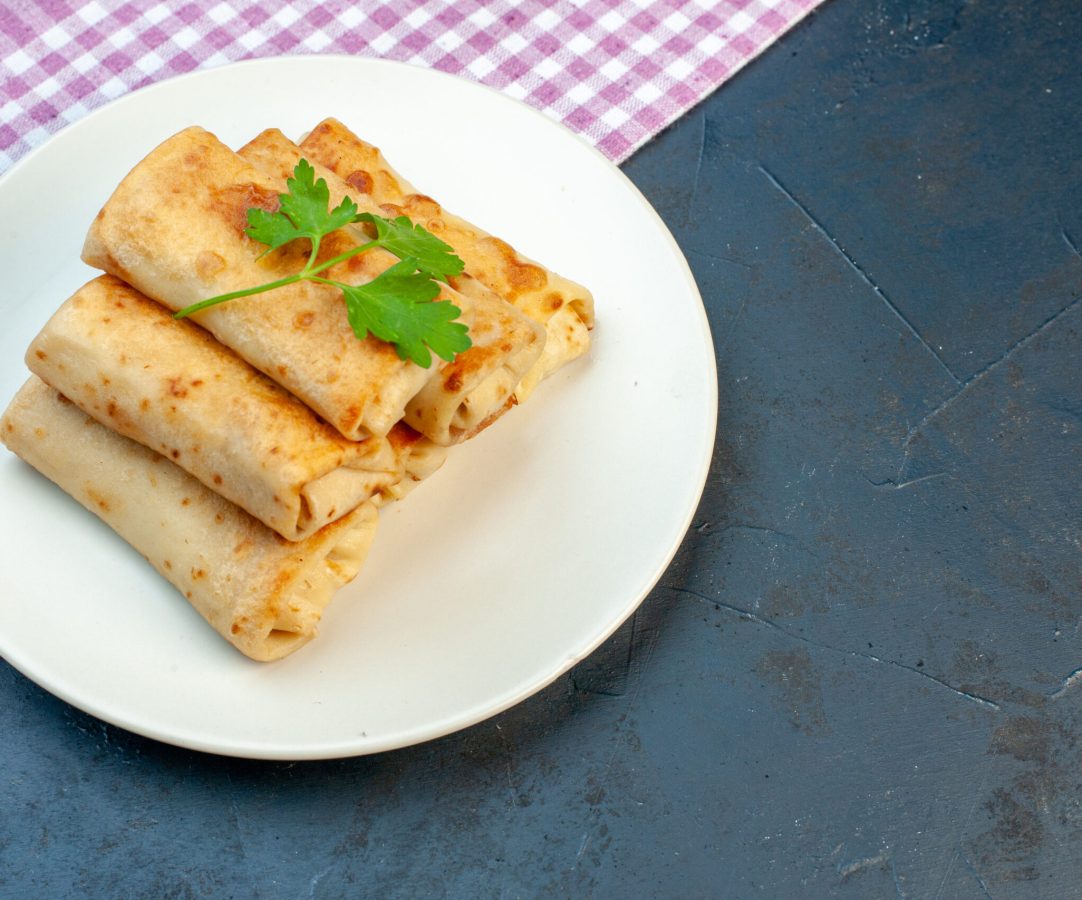 side-view-lavash-wraps-plate-with-green-purple-stripped-towel-right-side-black-background